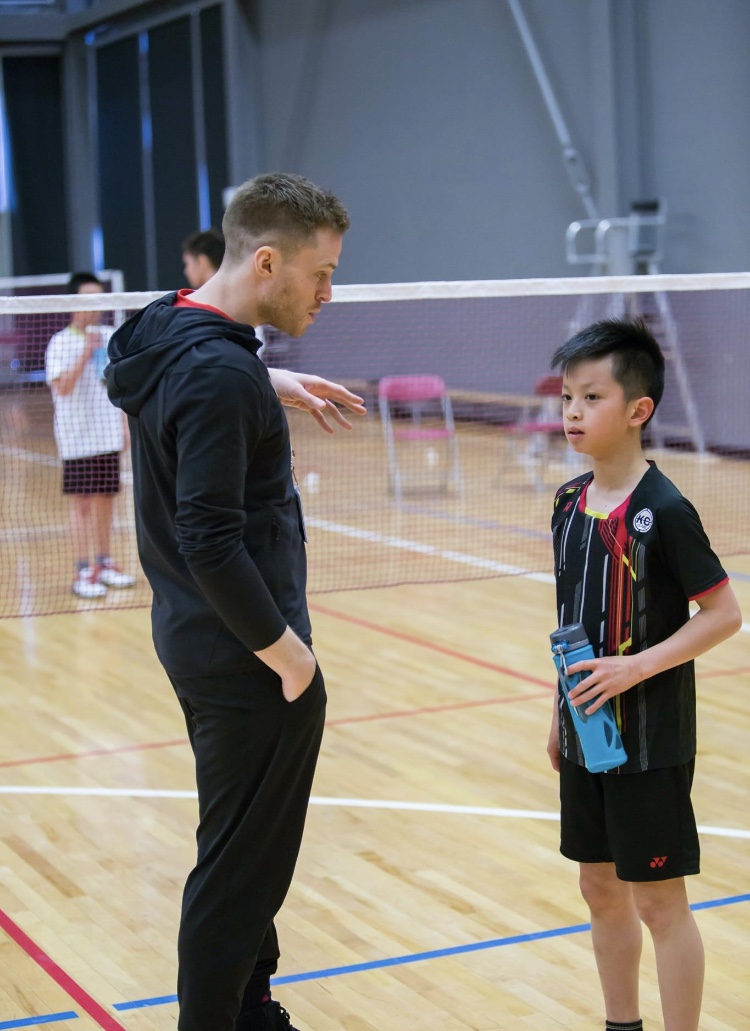 Andrew Smith coaching a junior badminton player on court
